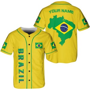 May include: Yellow baseball jersey with green accents and the word "BRAZIL" vertically down the front. The back features a green map of Brazil with the Brazilian flag and the text "YOUR NAME". The jersey has the Brazilian flag on the sleeves.