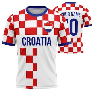 May include: White and red checkered Croatia soccer jersey with blue accents. The front features the word "CROATIA" in blue, a shield emblem, and a red and white checkered pattern. The back displays "YOUR NAME" and the number "0".
