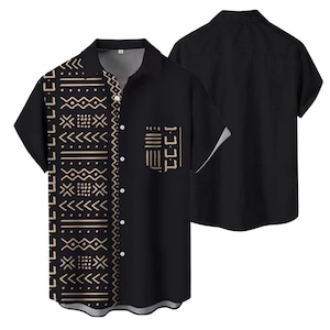 May include: Black short-sleeved shirt with a geometric pattern in tan and white on the left side and pocket. The shirt has a button-down front and a collar. A second shirt is visible in the background.