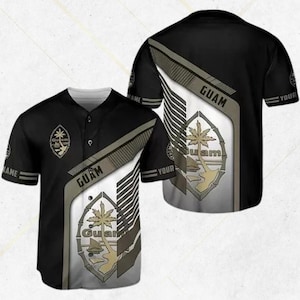 May include: Black baseball jersey with white and gray accents, featuring the word "Guam" and a Guam seal design. The jersey has short sleeves and a button-up front. The design is repeated on the back of the jersey.