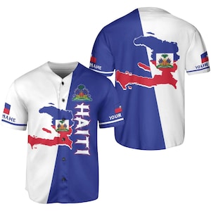 May include: A white and blue baseball jersey featuring the Haitian flag and map outline. The jersey has a button-up front and the word "HAITI" in white lettering. The sleeves have the word "NAME" and "YOUR" on them.
