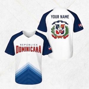 May include: White baseball jersey with navy blue sleeves and accents. The front displays "República Dominicana" in red lettering. The back features a coat of arms and the text "Your Name". A Dominican Republic flag is on the sleeve.