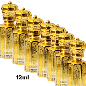 Puede incluir: Una colección de frascos de perfume dorados con tapas en forma de corona. Los frascos son transparentes con detalles decorativos dorados y el texto "12ml" es visible en la parte inferior. Los frascos están dispuestos en diagonal sobre un fondo blanco.