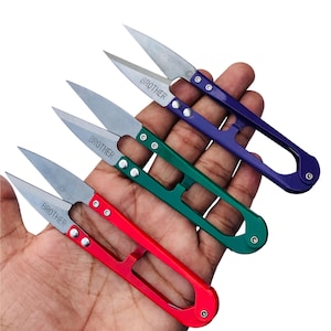 May include: Four thread snips in red, green, and purple. Each snip has a silver blade and the word "BROTHER" printed on it. The handles are made of metal and have a loop for easy handling.