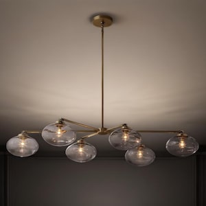 May include: A contemporary chandelier featuring six clear glass globe shades. The fixture has a brass finish and is suspended from the ceiling. Each globe contains a warm light bulb, creating a soft glow. The design is sleek and modern.