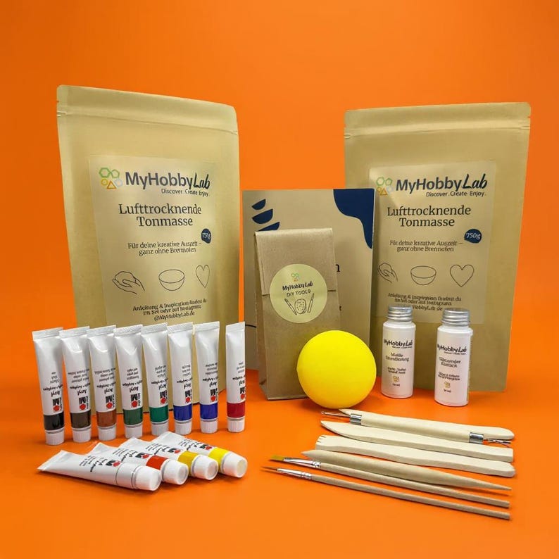May include: A craft kit with air-dry clay, paint tubes, brushes, and tools. The kit includes two bags of clay, two bottles, a yellow sponge, and a variety of paint colors. The text on the bags reads "MyHobbyLab".