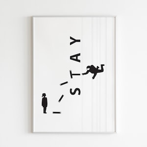 May include: Framed art print with a minimalist design. The black text reads "I STAY" with a silhouette of a person standing and another person reaching out. The artwork is set against a white background.