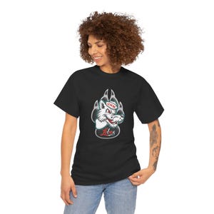 May include: Black t-shirt featuring a cartoon wolf mascot with the text "UNM Lobos". The wolf is white with red and green accents, wearing a hat. The design is set within a gray paw print.