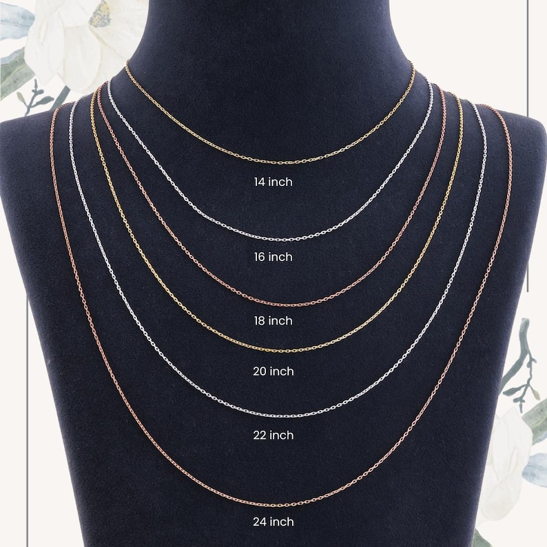 May include: A display of six delicate chain necklaces in varying lengths, from 35.5 cm to 61 cm. The chains are in gold, silver, and rose gold tones, presented on a black mannequin. Each chain is labeled with its length in inches.