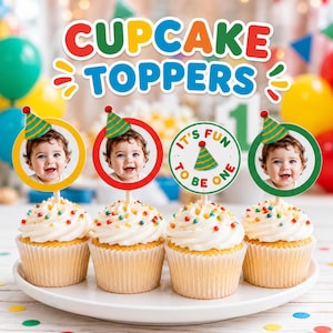 May include: Four cupcakes with white frosting and colorful sprinkles, each topped with a circular card. Three cards feature a photo of a baby wearing a party hat, and one card displays the text IT'S FUN TO BE ONE with a party hat illustration.