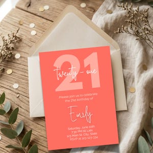 Puede incluir: Una invitación de cumpleaños número 21 de color coral con el texto "Twenty-one" en una fuente de escritura. La invitación incluye el nombre "Emily", los detalles del evento y un número de confirmación de asistencia. La invitación está dentro de un sobre crema.