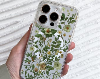 Könnte beinhalten: Transparente Handyhülle mit floralem Design mit grünen Blättern und gelben und grünen Blüten. Die Hülle hat einen transparenten Rand und bedeckt die Kamera und die Tasten des Telefons. Das Design ist eine botanische Illustration.