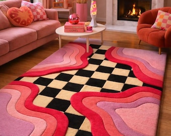 May include: A colorful area rug with a retro design. The rug features a checkerboard pattern in black and beige, with wavy stripes in shades of red, pink, and purple. The rug is placed on a wooden floor.
