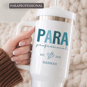 May include: A white insulated tumbler with a handle and straw, featuring the teal text PARA professional, a pencil inside a heart icon, the text EST. 2026, and the name HANNAH in teal. The word PARAPROFESSIONAL appears in a dark box above.
