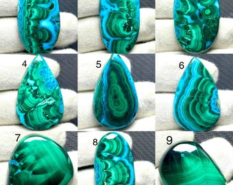 May include: A collection of nine polished malachite and chrysocolla gemstones in various shapes, including ovals, teardrops, and rounded forms. Each stone displays distinct green and blue banded patterns, numbered one through nine in black text.
