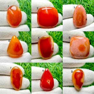 Pode incluir: Uma coleção de nove pedras preciosas de cornalina polidas em várias formas, incluindo oval, quadrada e gota. Cada pedra exibe tons vibrantes de laranja e vermelho com faixas naturais e qualidades translúcidas, numeradas de um a nove.