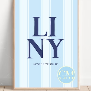 May include: A framed print with a light blue and white striped background. The words "LI NY" are in navy blue, with the coordinates 40.7891° N, 73.1350° W below. A circular logo with text is in the bottom right corner.