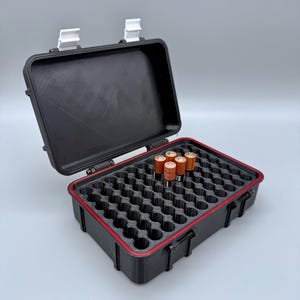 Könnte beinhalten: Schwarze Batterie-Aufbewahrungsbox mit roter Umrandung, geöffnet, um einen Schaumstoffeinsatz mit mehreren Schlitzen freizulegen. Sechs AA-Batterien sind sichtbar. Das Gehäuse hat weiße Verschlüsse und dient zum Schutz und zur Organisation von Batterien.