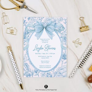 Może przedstawiać: Zaproszenie na baby shower z jasnoniebieską kokardą i kwiatowym wzorem. Zaproszenie zawiera tekst "Please join us for a Baby Shower in honor of Leigha Stevens" oraz szczegóły wydarzenia. Artykuły papiernicze otaczają zaproszenie.