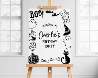 Könnte beinhalten: Ein weißes Schild auf einer Holzstaffelei mit schwarzen Halloween-Illustrationen und Text. Auf dem Schild steht "BOO!" und "Willkommen zu Charlies Geburtstagsparty." Enthält einen Geist, Fledermäuse, einen Teddybären, einen Hexenhut, eine schwarze Katze und einen Kürbis.