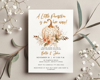 Puede incluir: Una tarjeta de invitación rectangular blanca para baby shower con una ilustración en acuarela de una calabaza blanca con lunares dorados rodeada de flores y hojas de otoño. El texto dice A Little Pumpkin is on her way!