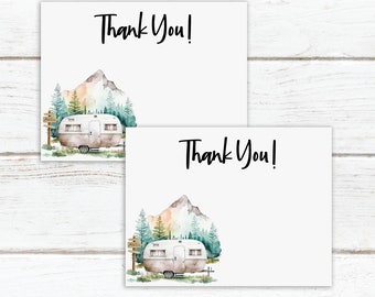 May include: Two white thank you cards featuring a watercolour illustration of a vintage camper, mountains, and trees. The words "Thank You!" are written in black script. The cards are on a white wooden surface.