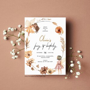 May include: A fairy-themed birthday invitation with watercolour illustrations of fairies and flowers. The invitation features the text "Olivia's fairy 1st birthday" and event details. The design includes a floral wreath and is set against a soft, neutral background.