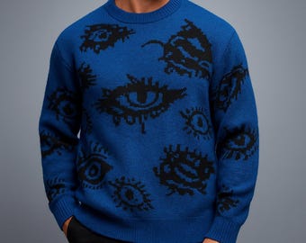 Peut inclure: Un pull bleu avec un col rond et des manches longues. Le pull présente un motif répété d'yeux noirs. Le vêtement est en maille et convient aux températures plus fraîches.