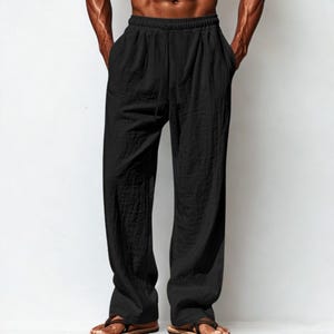 Puede incluir: Pantalones de lino negros con corte relajado. Los pantalones tienen cintura con cordón y bolsillos. La tela parece ligera y transpirable, adecuada para climas cálidos. Los pantalones se muestran con sandalias.