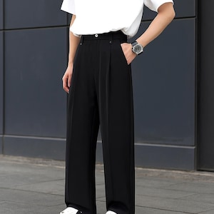May include: Black wide-leg pants with a high waist. The pants are paired with a white t-shirt and white sneakers. The pants have a classic, tailored design.