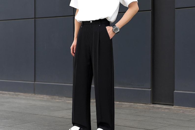 May include: Black wide-leg pants with a high waist. The pants are paired with a white t-shirt and white sneakers. The pants have a classic, tailored design.