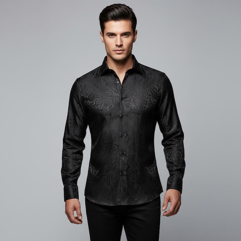 May include: A black long-sleeve shirt with a subtle paisley pattern. The shirt has a classic collar and button-down front. The fabric appears to have a slight sheen, adding to its formal appearance. The shirt is paired with black pants.