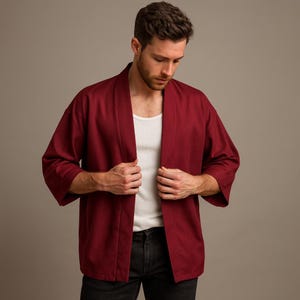 May include: A burgundy kimono-style jacket with three-quarter sleeves. The open-front jacket is worn over a white tank top and black jeans. The jacket has a relaxed fit and a simple, elegant design.
