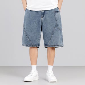 May include: Light blue denim shorts with a relaxed fit. The shorts feature unique geometric stitching details and a classic five-pocket design. The model is wearing white sneakers and socks.