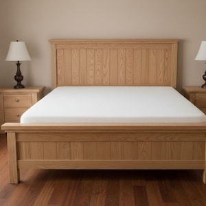 May include: A light-colored wooden bed frame with a matching headboard and footboard. The bed has a white mattress and is flanked by two matching nightstands with lamps. The room has a neutral color palette.