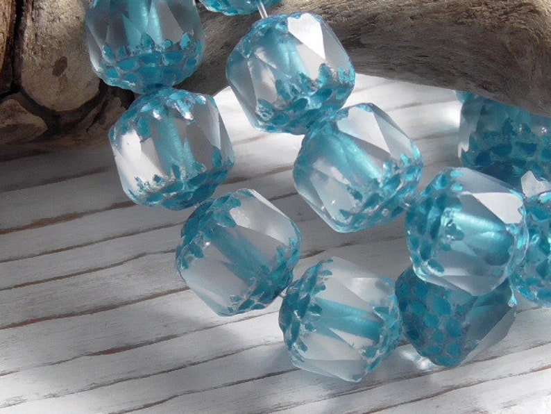 Pode incluir: Um fio de contas de vidro facetadas de cor azul claro com acabamento fosco. As contas s&atilde;o facetadas e t&ecirc;m um brilho ligeiramente iridescente.