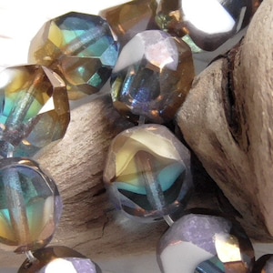 May include: A strand of iridescent glass beads in shades of blue, green, and brown. The beads are faceted and have a shimmering effect.