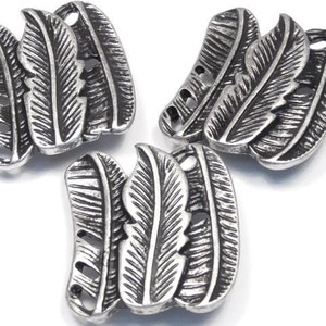 May include: Three silver-toned metal buttons with a feather design. Each button has three feathers with a textured surface.