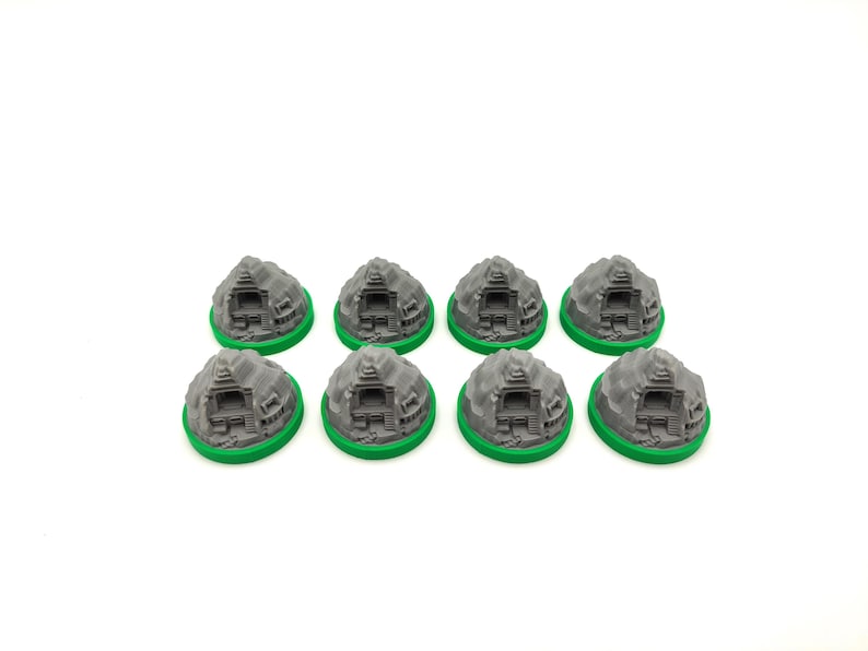 May include: Eight gray miniature temple models with green bases are arranged on a white surface. Each model features detailed architectural elements, resembling ancient structures. The models are designed for tabletop gaming or model building.