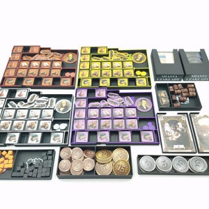 May include: A board game with various components, including cards, tokens, and player pieces, organized in black trays. The game pieces are in shades of brown, yellow, purple, and orange. The game includes coins and dice.