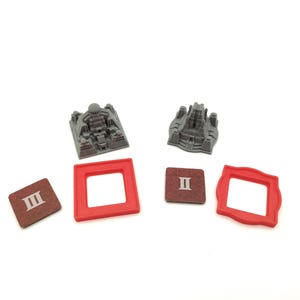 May include: A collection of board game components, including two gray miniature building models, two red square frames, and two brown square tiles with Roman numerals. The items are arranged on a white surface.