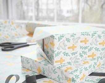 May include: Two gift boxes wrapped in white paper with a pattern of yellow crosses, white doves, and green leaves. A roll of matching wrapping paper and scissors are visible. Black ribbon is in the foreground.