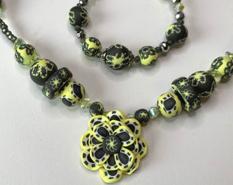 Black and lemon ceramic statement necklace, handmade large boho flower pendant with patterned beads, tactile and distinctive, not for profit