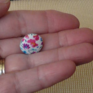 May include: A white button with a floral pattern in pink, blue, and green.