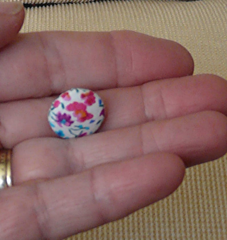 May include: A white button with a floral pattern in pink, blue, and green.