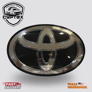 May include: Oval-shaped Toyota emblem with a chrome finish and a black background. The Toyota logo is prominently displayed in the center. The image also includes the text "CYPTEX" and "Used Auto Parts".