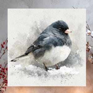 May include: A watercolor painting of a small bird with a black head and back, and a white belly, standing in the snow. The artwork is displayed above a rustic wooden shelf with candles, pinecones, and decorative branches.
