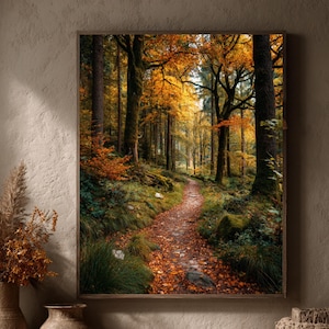 Könnte beinhalten: Ein gerahmter Druck eines Waldweges im Herbst. Der Weg ist mit Herbstlaub bedeckt und führt in einen Wald aus hohen Bäumen mit gelben und orangefarbenen Blättern. Der Druck wird an einer neutralfarbenen Wand mit dekorativen Vasen, Kürbissen und einem geflochtenen Korb im Vordergrund präsentiert.