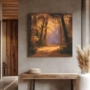 Könnte beinhalten: Ein quadratischer Wandkunstdruck, der einen Waldweg im Herbst zeigt, mit goldgelbem und orangefarbenem Laub an den Bäumen und auf dem Boden, wobei weiches, dunstiges Licht durch das dichte Blätterdach in die Mitte der Waldszene fällt.
