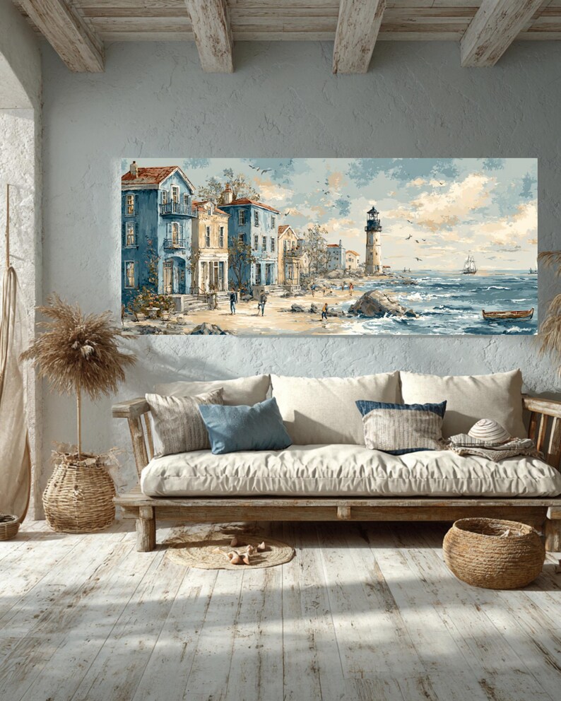 May include: Coastal landscape painting featuring buildings in shades of blue and yellow, a lighthouse, and a sailboat on the sea. The artwork is displayed above a wooden sofa with pillows and a woven basket, creating a serene, nautical-themed interior.